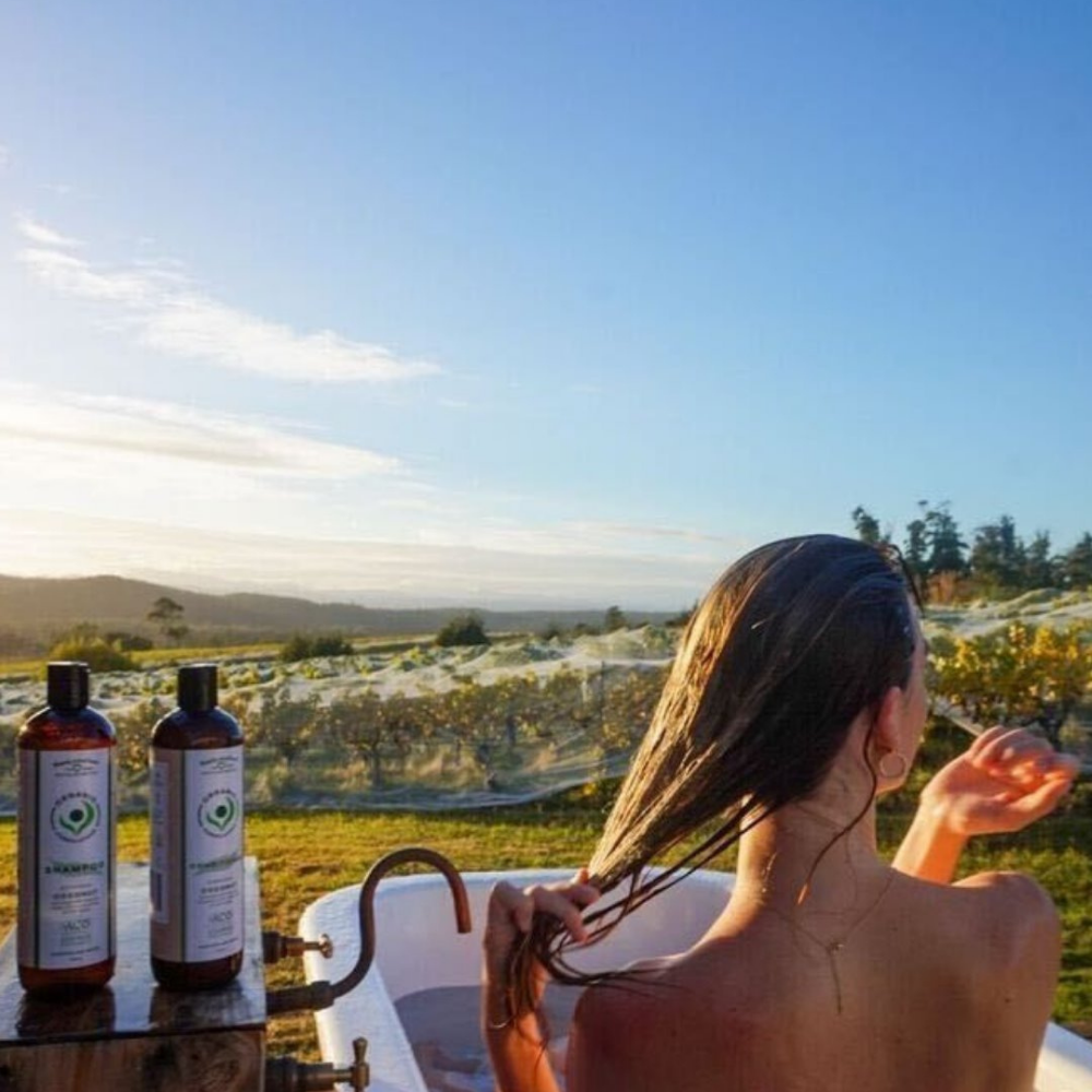 Organic Formulations Sensitive Conditioner bottle overlooking an idyllic valley with greenery