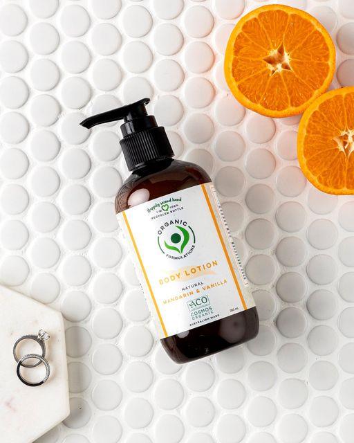“Vanilla & Mandarin body lotion bottle set beside mandarin fruit slices 